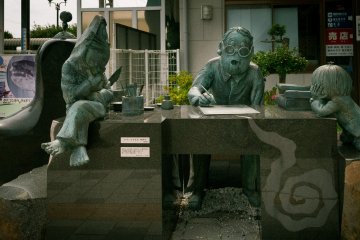 A lifesize stone and bronze statue of the artist at work, flanked by his creations.