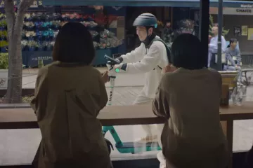 Two people looking out the window of a cafe, seeing someone glide by on a LUUP scooter