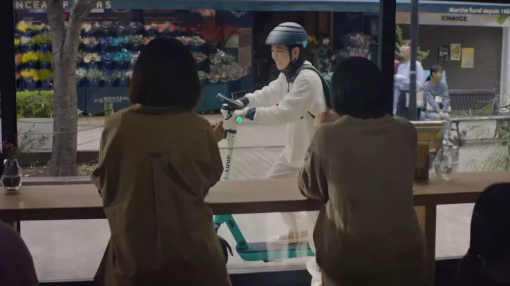 Two people looking out the window of a cafe, seeing someone glide by on a LUUP scooter