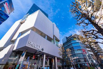 The exterior of Shibuya PARCO on a sunny day, towering into the blue sky