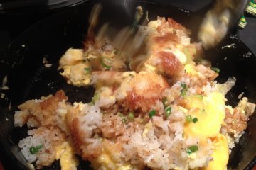 <p>Stir your garlic fried rice to mix up the eggs, onions and rice together</p>