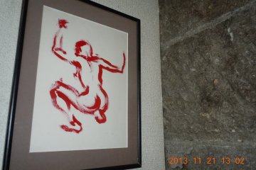 The washroom is outside and around the back. It's clean and nicely decorated. These sketches decorate the restaurant. This one hangs above the toilet. Can you guess what kind of toilet it is?