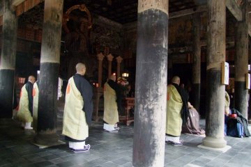 Priests wearing light yellow robes had been standing patiently, waiting for the chief priest. Flames of candles on the altar were flickering. Then, the chief priest came into the hall. A solemn low tone of voices began to chant.