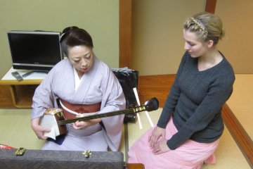 Ms. Shisenya Madoka, giving Shamisen training to a foreign apprentice. She is a master of Shamisen as well as a Geisha.