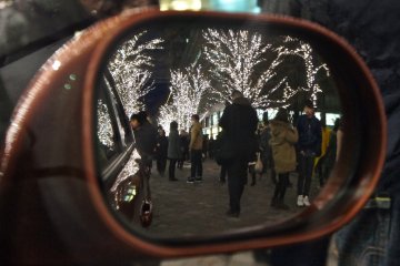 Orang-orang di jalan-jalan, yang sedang berbelanja sambil menikmati iluminasi, menambah keceriaan nuansa Natal di belakang Marunouchi Building