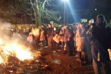 Para pengunjung menghangatkan diri mereka pada malam yang dingin