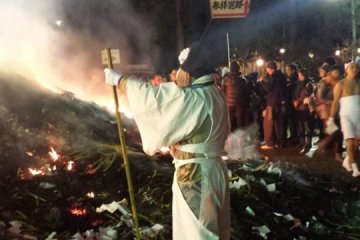 Seorang pendetaprie mengamati api unggun. Tidak seperti para peserta, sang biksu mengenakan pakaian lengkap.