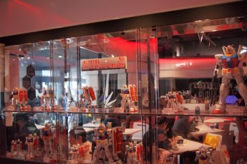 <p>โมเดลพลาสติก (GUNPLA) หลากหลายขนาดวางเรียงรายในตู้โชว์</p>