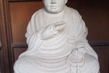 <p>Sitting serenely in his shelter near the entrance to one of the temples</p>