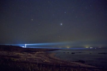 <p>Lampu di malam hari menerangi pantai, tapi bintang-bintang masih bersinar terang di atas Tsunoshima yang berpenduduk jarang</p>
